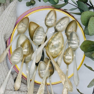 Puede incluir: Una colección de cucharas de plata vintage con varias frases grabadas en ellas, incluyendo "Te amo", "Pero primero el café", "Las rosas son rojas las violetas son azules", y "Helado y Netflix".