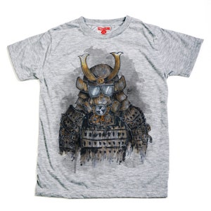 May include: A gray t-shirt featuring a detailed illustration of a samurai warrior wearing a gas mask and sunglasses. The artwork is in shades of brown, gold, and gray, with a radiation symbol on the chest. The shirt has a red tag on the collar.