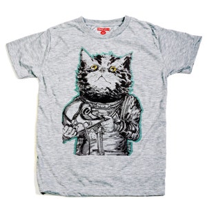 May include: A gray t-shirt with a graphic of a cat wearing a space suit and holding a helmet. The cat has yellow eyes and is looking up. The text "SIG" is on the bottom right of the graphic.