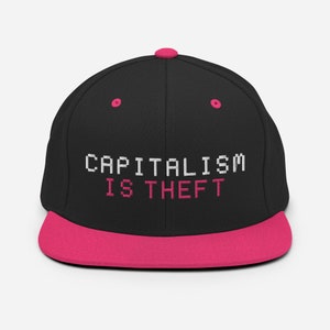 May include: Black flat-brimmed baseball cap with a hot pink brim and button. The cap features the text "CAPITALISM IS THEFT" embroidered in white and pink pixelated font.