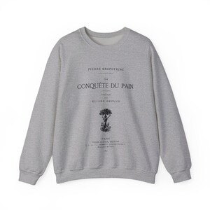 Könnte beinhalten: Ein graumeliertes Sweatshirt mit Rundhalsausschnitt und schwarzem Aufdruck, der PIERRE KROPOTKINE LA CONQUÊTE DU PAIN, PREFACE PAR ELISEE RECLUS, PARIS sowie weiteren kleinen Text enthält, ergänzt durch eine schwarze Grafik eines Baumes.