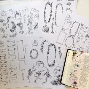 May include: Black and white botanical illustrations on white paper, including floral wreaths, banners, and individual plant elements. The phrase "the joyful journal" is written on some sheets. An open book with floral art is also visible.