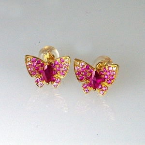 May include: A pair of gold butterfly earrings with pink and red gemstones.