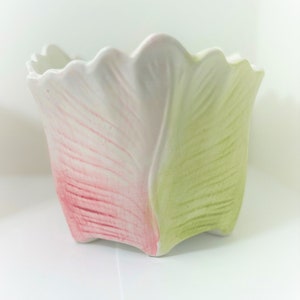 May include: A white ceramic flower pot with pink and green painted tulip designs.
