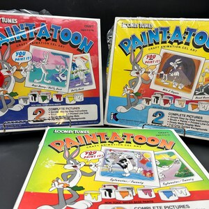 Puede incluir: Tres cajas de kits de arte de cel de animación Paint-A-Toon de Looney Tunes. Cada caja presenta a Bugs Bunny y un personaje de dibujos animados diferente. Las cajas tienen instrucciones para completar dos imágenes con pinturas a base de agua.