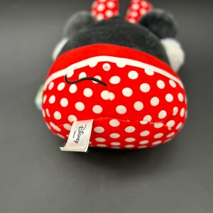 Puede incluir: Un juguete de peluche rojo y blanco con lunares, con una cara y orejas negras. El juguete tiene una etiqueta blanca que dice "Disney".