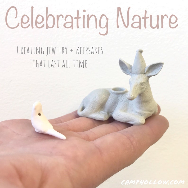 Pode incluir: Uma m&atilde;o segura duas pequenas figuras de cer&acirc;mica de cor clara: um p&aacute;ssaro e um veado. O veado est&aacute; deitado com um chap&eacute;u c&ocirc;nico. O texto "Celebrating Nature" e "Creating Jewelry + Keepsakes That Last All Time" &eacute; exibido no fundo.