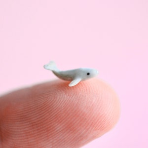May include: A small white ceramic whale figurine on a finger.