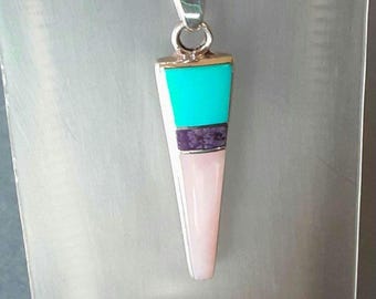 May include: A silver pendant necklace with a geometric design. The pendant features a turquoise top, a purple band, and a pink bottom. The necklace is suspended from a silver chain, creating a striking contrast.