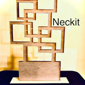May include: A wooden geometric design with a cutout pattern. The design is brown and has a base. The word "Neckit" is printed on the right side of the design.