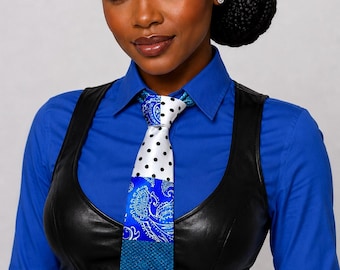 May include: A patterned tie with a mix of designs, including polka dots, paisley, and a houndstooth pattern. The tie is a combination of blue, white, and black. The tie is worn with a blue button-down shirt and a black vest.