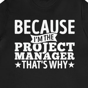 May include: Black t-shirt with white text that reads "Because I'm the Project Manager That's Why" with a star on either side of the last phrase.