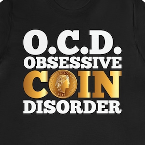 May include: Black t-shirt with white text that reads "O.C.D. OBSESSIVE COIN DISORDER". A gold coin with a woman's profile is in the center of the text.