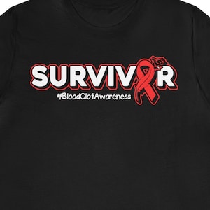 Op de afbeelding: Zwart T-shirt met het woord "SURVIVOR" in witte letters met een rood lint en de tekst "#BloodClotAwareness" eronder.