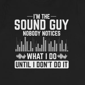 May include: Black t-shirt with white text that reads "I'm the Sound Guy Nobody Notices What I Do Until I Don't Do It". The text is surrounded by a graphic of sound waves.