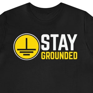 May include: Black t-shirt with a yellow circle containing a ground symbol and the text "STAY GROUNDED" in white.
