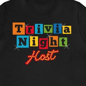 May include: Black t-shirt with a colorful graphic that says "Trivia Night Host" in a retro style.