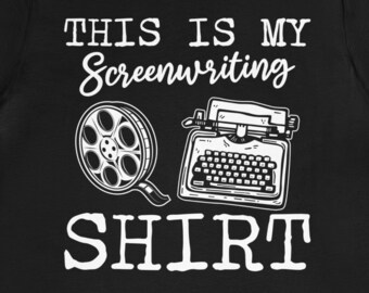 May include: Black t-shirt with white text that reads "This is my Screenwriting Shirt". The shirt features a black and white illustration of a film reel and a typewriter.