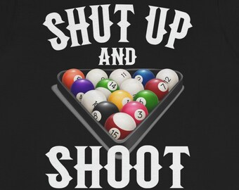 Op de afbeelding: Zwart T-shirt met witte tekst die "Shut Up and Shoot" zegt met een afbeelding van een biljarttafel met biljartballen.