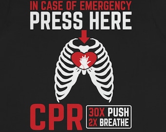 May include: Black t-shirt with a white skeleton ribcage and a red heart with a hand inside. The text "IN CASE OF EMERGENCY PRESS HERE" is above the ribcage and an arrow points to the heart. Below the ribcage is the text "CPR 30X PUSH 2X BREATHE".