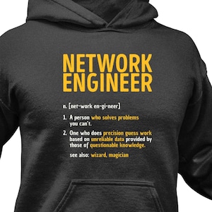 Könnte beinhalten: Ein dunkelgrauer Kapuzenpullover mit dem Text "NETWORK ENGINEER" in Gelb. Der Text ist definiert als "[ner-work en-gi-neer]" und enthält eine Liste mit zwei Definitionen in Gelb. Die erste Definition lautet "Eine Person, die Probleme löst, die du nicht lösen kannst." Die zweite Definition lautet "Jemand, der präzise Vermutungsarbeit auf der Grundlage unzuverlässiger Daten macht, die von Personen mit fragwürdigem Wissen bereitgestellt werden." Der Text enthält auch "siehe auch: Zauberer, Magier" in Gelb.