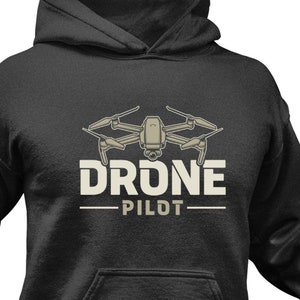 Może przedstawiać: Czarna bluza z kapturem z grafiką drona i napisem "Drone Pilot" w kolorze białym.