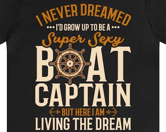 Peut inclure: T-shirt noir avec l'inscription "I NEVER DREAMED... I'D GROW UP TO BE A... Super Sexy BOAT CAPTAIN BUT HERE I AM LIVING THE DREAM." Le motif comprend un gouvernail de navire marron et beige.