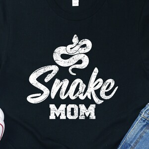 May include: Black t-shirt with a white distressed graphic of a snake and the text "Snake Mom".