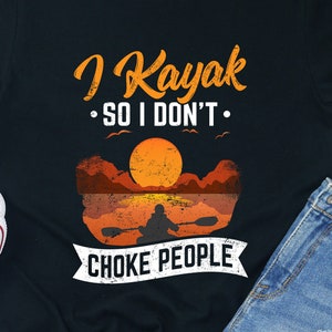 Puede incluir: Camiseta negra con un gráfico de una puesta de sol y una persona en kayak. El texto "I Kayak So I Don't Choke People" está impreso en la camiseta.