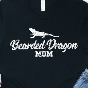 Puede incluir: Camiseta negra con una silueta blanca de un dragón barbudo y el texto "Bearded Dragon MOM".
