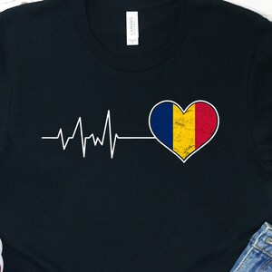 May include: Black t-shirt with a white heartbeat graphic and a red, yellow, and blue heart with a distressed look. The heart is the flag of Romania.
