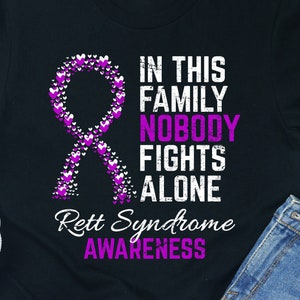May include: Black t-shirt with a purple ribbon made of hearts and the text "In this family nobody fights alone. Rett Syndrome Awareness."