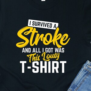 Peut inclure: T-shirt noir avec du texte jaune qui dit "J'ai survécu à un AVC et tout ce que j'ai eu c'est ce t-shirt pourri".
