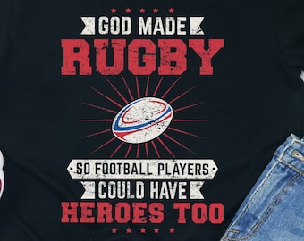 May include: Black t-shirt with a white rugby ball graphic and the text "God Made Rugby So Football Players Could Have Heroes Too".