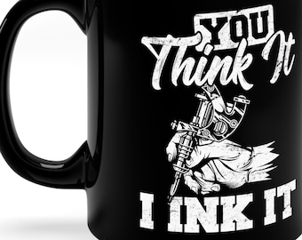 May include: Black ceramic coffee mug with a white design that says "You Think It I Ink It" and a tattoo machine in a hand.