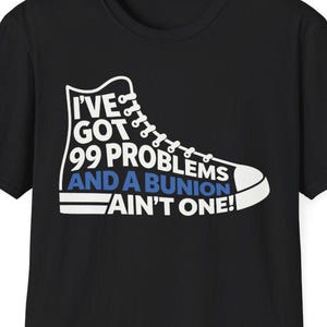 Peut inclure: T-shirt noir avec un motif blanc et bleu d'une chaussure de sport montante. Le texte sur le t-shirt se lit comme suit : "J'AI 99 PROBLÈMES ET UN OIGNON, CE N'EST PAS L'UN D'EUX !"