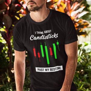 May include: Black t-shirt with a white graphic that says "I think about candlesticks past my bedtime". The graphic also includes a stylized candlestick chart with red and green bars.