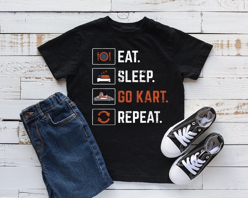 Puede incluir: Camiseta negra con texto blanco que dice "Comer. Dormir. Ir en karting. Repetir."
