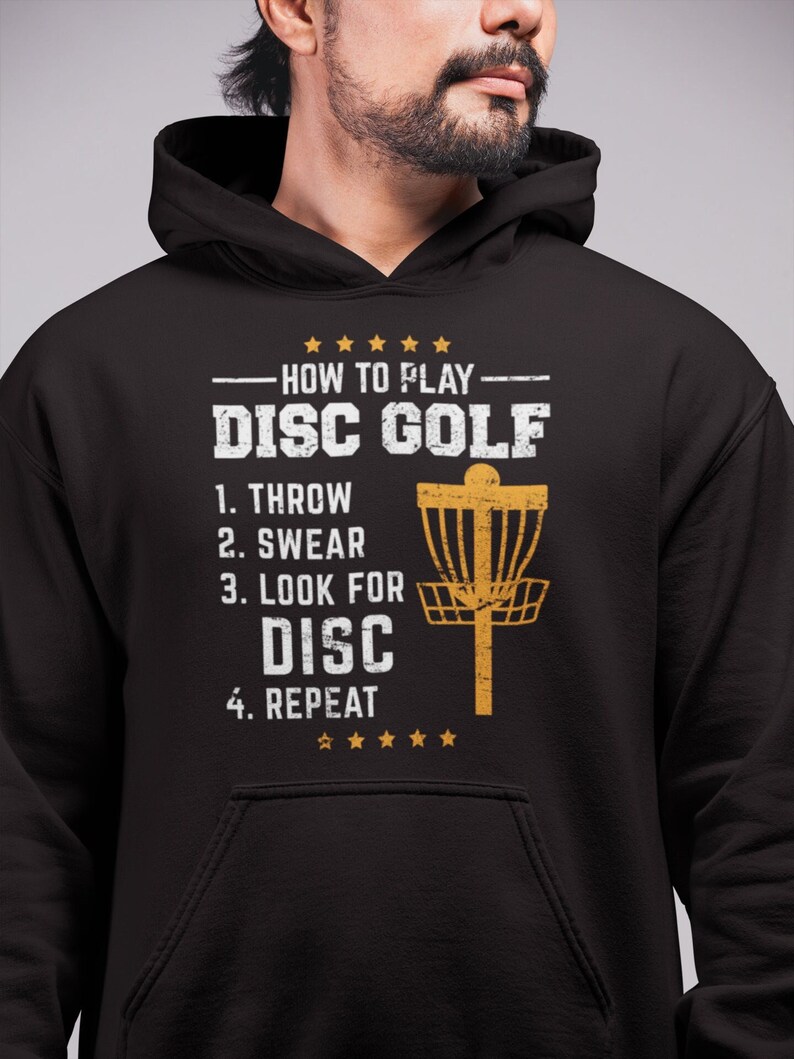 May include: Black hoodie with a distressed gold graphic that says "How to Play Disc Golf" with a list of steps: "1. Throw, 2. Swear, 3. Look for Disc, 4. Repeat".
