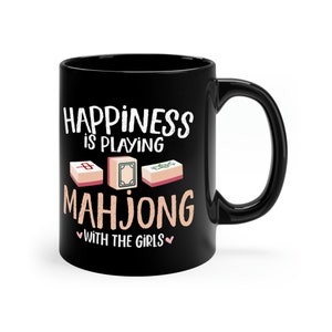 May include: Black ceramic mug with a white graphic that says "Happiness is playing Mahjong with the girls". The graphic also includes three mahjong tiles.