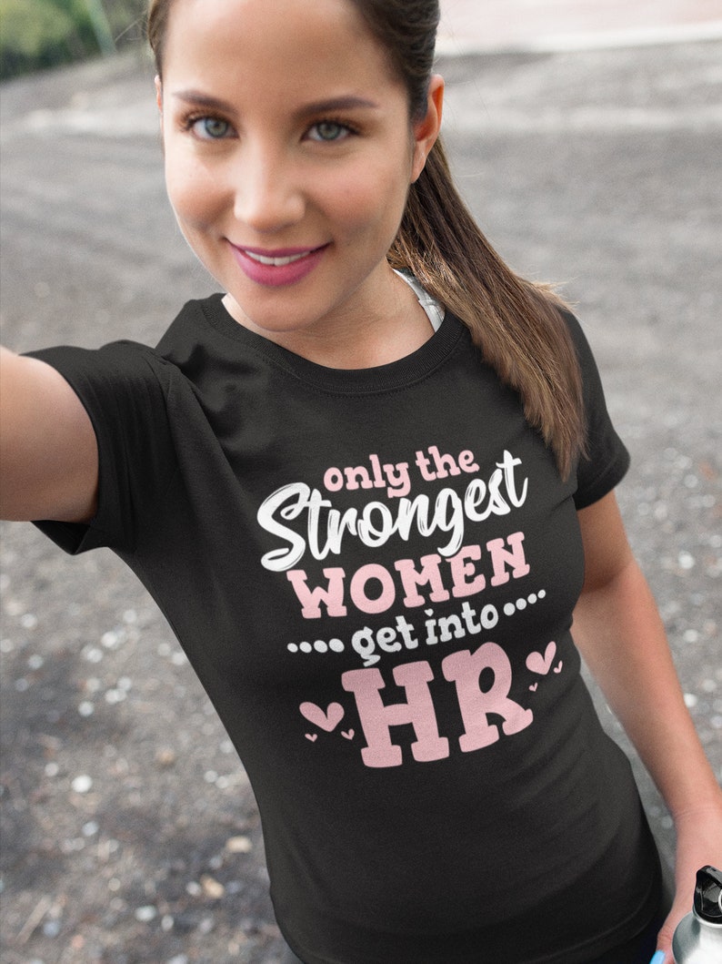 May include: Black t-shirt with pink text that reads "Only the Strongest Women... get into... HR" with pink hearts on either side of the text.