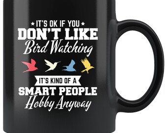 May include: Black ceramic mug with a white handle. The mug features the text "IT'S OK IF YOU DON'T LIKE Bird Watching" and "IT'S KIND OF A SMART PEOPLE Hobby Anyway" in white. Four colorful bird silhouettes are below the text.