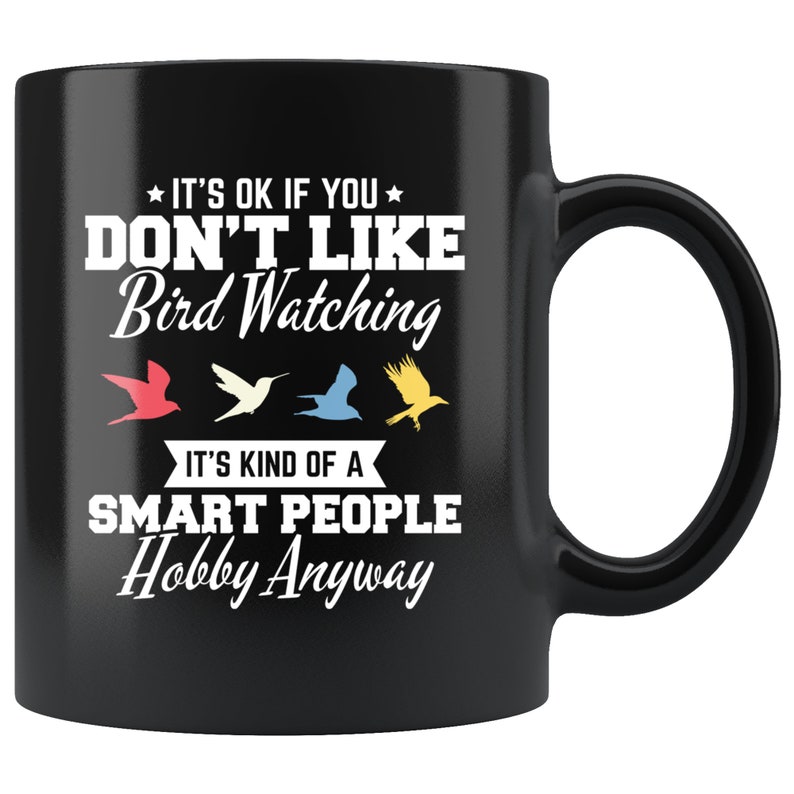 May include: Black ceramic mug with a white handle. The mug features the text "IT'S OK IF YOU DON'T LIKE Bird Watching" and "IT'S KIND OF A SMART PEOPLE Hobby Anyway" in white. Four colorful bird silhouettes are below the text.