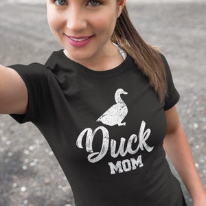 Puede incluir: Una camiseta negra con una silueta de pato blanca y el texto "Duck Mom" en una fuente blanca desgastada.
