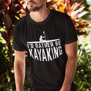 May include: Black t-shirt with a white graphic of a person kayaking and the text "I'd rather be kayaking".