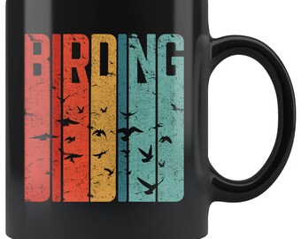 May include: Black ceramic coffee mug with a vintage-style graphic of the word "BIRDING" in white letters with a rainbow stripe background and silhouettes of birds flying.