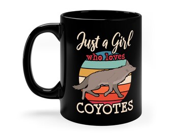 May include: Black coffee mug with a white graphic design that says "Just a Girl who loves Coyotes" with a silhouette of a coyote running in front of a sunset.