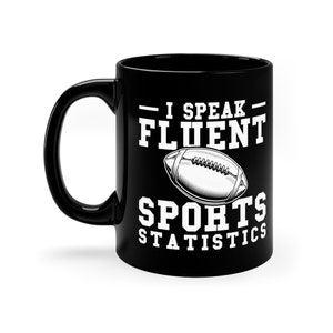 May include: Black ceramic coffee mug with a white design that says "I speak fluent sports statistics" with a football graphic.