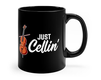 May include: Black ceramic coffee mug with a white graphic of a cello and the text "Just Cellin'"