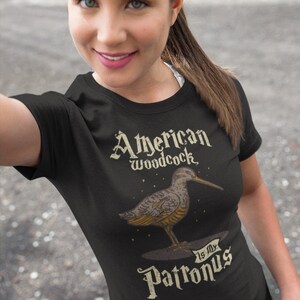 May include: A black t-shirt with a graphic of an American Woodcock bird and the text "American Woodcock is my Patronus".